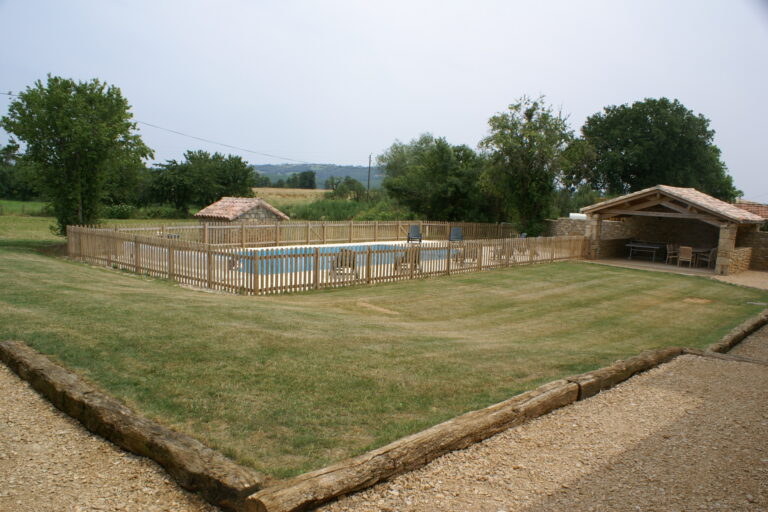 The fenced 12m x 6m swimming pool beside the open stone barn