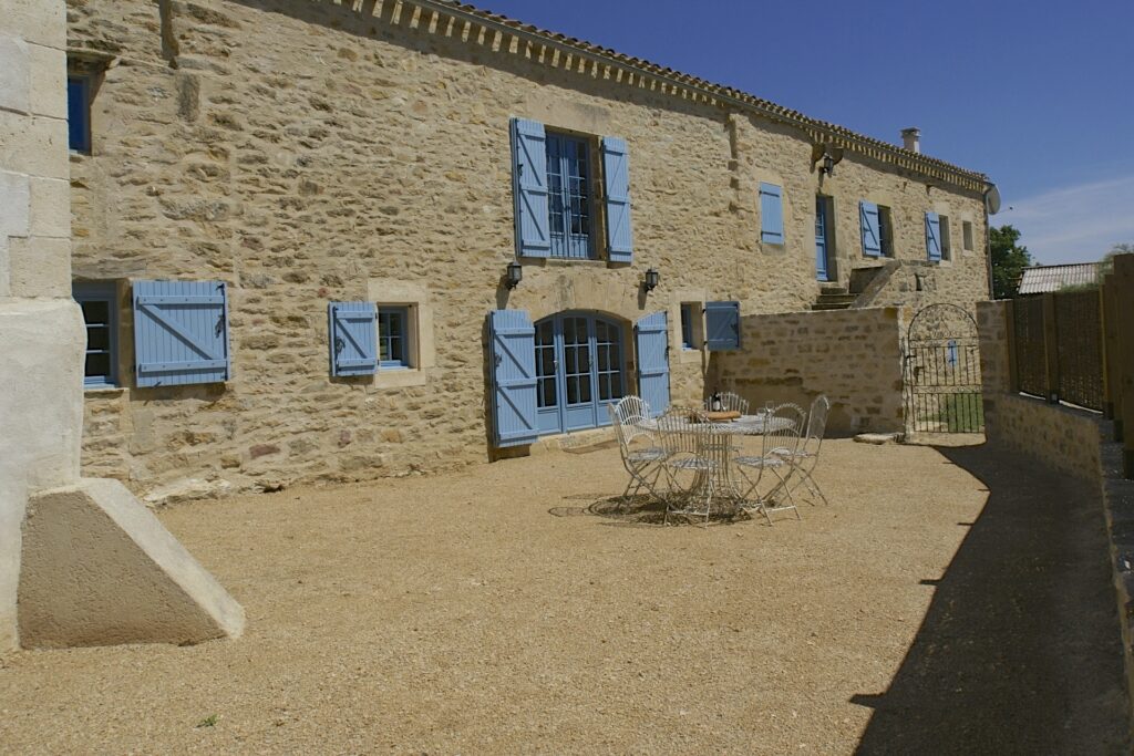 The restored courtyard with pale blue shutters and a table for six