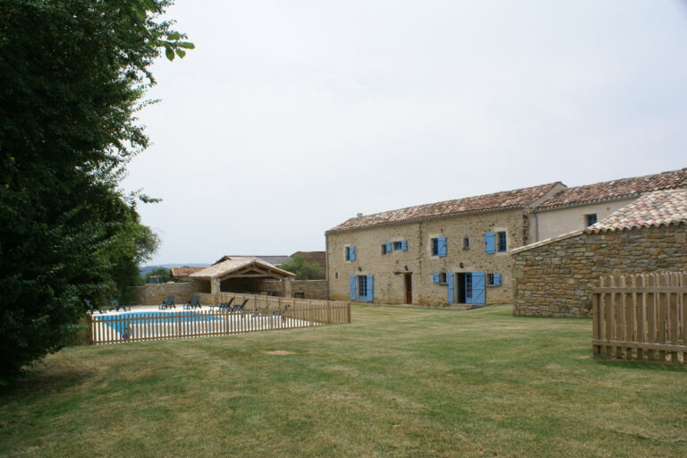 The farmhouse, barn and fenced swimming pool seen across the lawn
